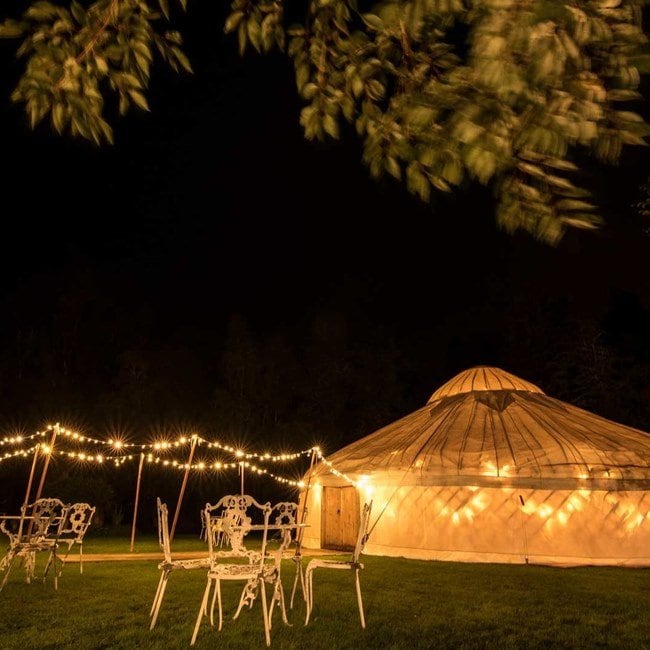 Kelburn Garden Party - fairy lights, table and chairs outside a yurt
