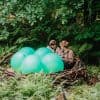 two women sit in nest with large green bouncy balls, installation by artist ashley dudley-smith